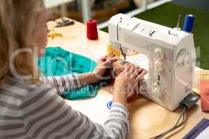 Female fashion designer using sewing machine on a table