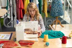 Female fashion designer using sewing machine on a table