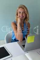 Businesswoman looking at camera while working at desk in office