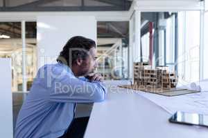Male architect looking at architectural model at table in a modern office