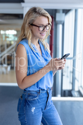 Happy beautiful businesswoman using mobile phone in a modern office