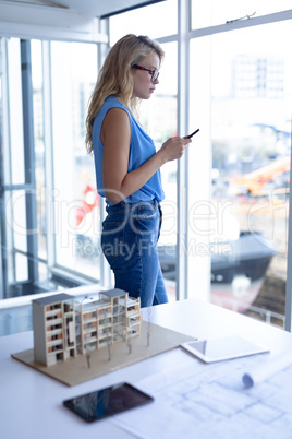 Female architect using mobile phone in a modern office