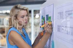 Female architect working over blueprint on whiteboard in a modern office