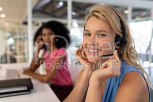 Female customer service executive talking on headset at desk in office
