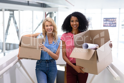 Female executives standing with cardboard boxes in office