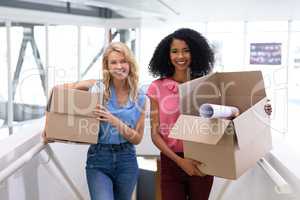 Female executives standing with cardboard boxes in office