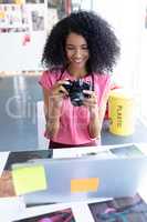 Female graphic designer reviewing photos on digital camera at desk