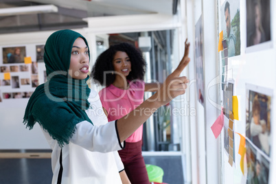 Female graphic designers discussing over photographs in office