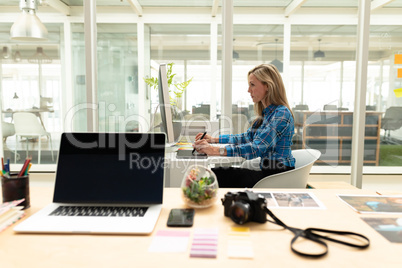 Female graphic designer using graphic tablet at desk