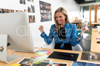 Happy female graphic designer celebrating success at desk