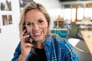 Female graphic designer talking on mobile phone in office