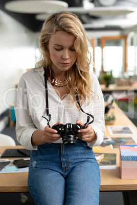 Female graphic designer reviewing photos on digital camera in a modern office