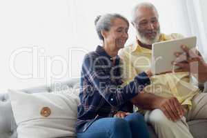 Couple sitting on couch while using a tablet