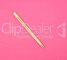 two wooden chopsticks on a pink background