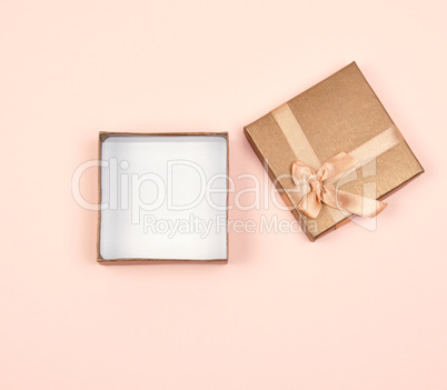 open golden square gift box with a bow on a beige background