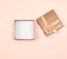 open golden square gift box with a bow on a beige background