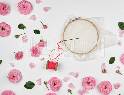 round wooden hoop and a red thread with a needle