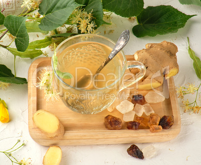 transparent cup with tea from ginger  and linden on a white wood