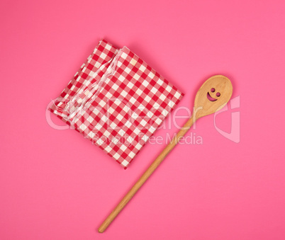 wooden spoon with a carved face on a red kitchen towel