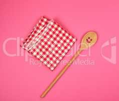 wooden spoon with a carved face on a red kitchen towel