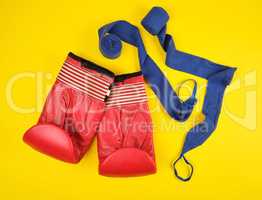 pair of red leather boxing gloves and blue textile bandage