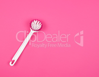 kitchen brush with white plastic handle on a pink background