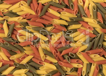 Color penne pasta. Tomato, spinach and wheat pastas as backgroun