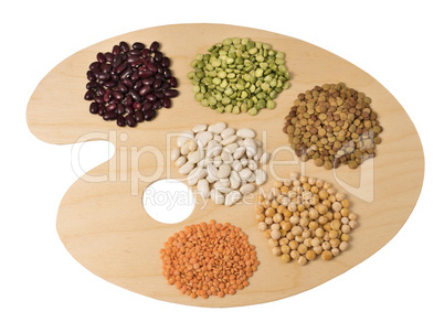 Collection of legumes on wooden art palette, isolated on white b