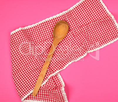 wooden spoon on a red kitchen towel, pink background