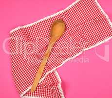 wooden spoon on a red kitchen towel, pink background