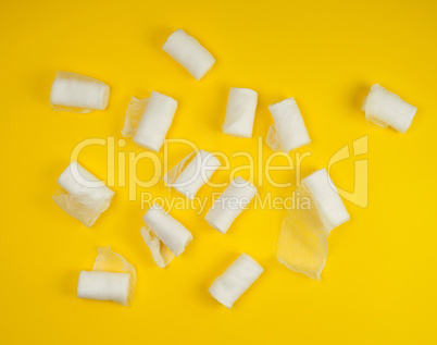 rolled up white sterile medical bandages on a yellow background