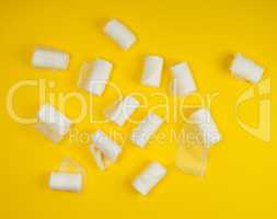 rolled up white sterile medical bandages on a yellow background