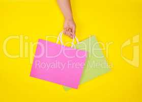 hand holding two paper shopping bags on a yellow background