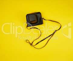 old film camera in a brown leather case on a yellow background