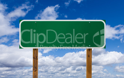 Blank Green Road Sign with Wooden Posts Over Blue Sky and Clouds