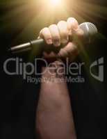 Vertical Microphone Clinched Firmly in Male Fist on a Black Back