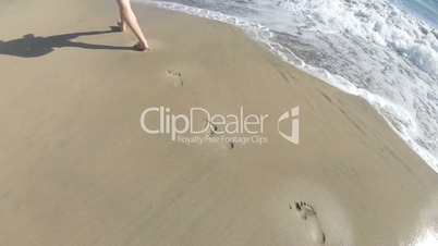 Man walks on sandy beach and leave the trace in sand