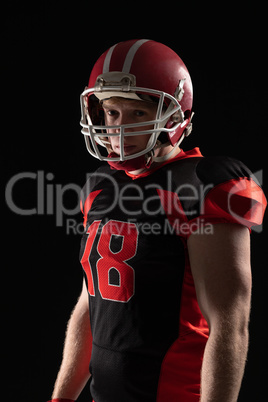 American football player in helmet standing against black background