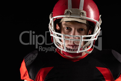 American football player in helmet standing against black background