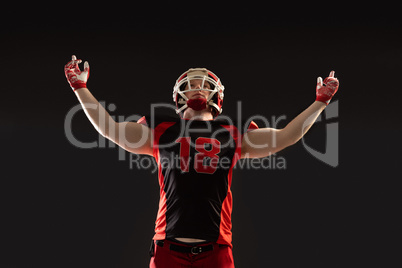 American football player standing against black background