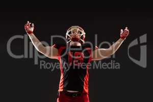 American football player standing against black background