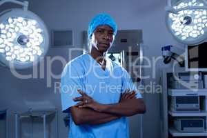 Male surgeon with arms crossed standing in operating room of hospital