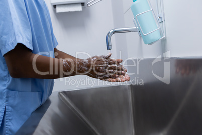 Male surgeon washing hands in sink at hospital