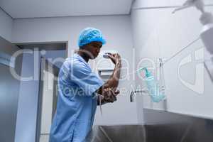 Male surgeon washing hands in sink at hospital