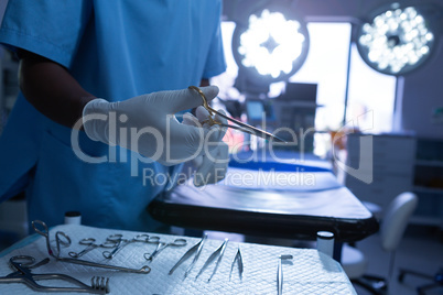 Surgeon holding surgical scissor in operating room of hospital