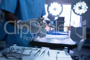 Surgeon holding surgical scissor in operating room of hospital