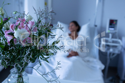 Flower in a vase on table in front of hospital bed