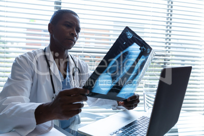 Male doctor examining x-ray report at desk