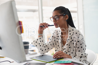 Female Graphic designer using graphic tablet at desk