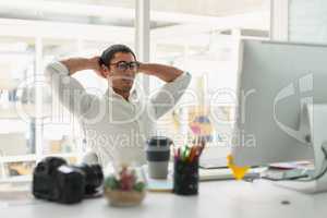 Male graphic designer sitting with hands behind hand at desk